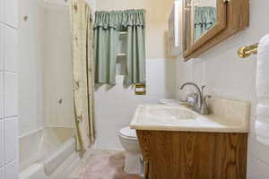 Bathroom with tile walls, vanity, and shower / tub combo with curtain