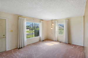 Spare room featuring carpet flooring, a textured ceiling, and a textured wall