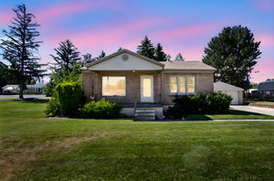 Ranch-style house featuring brick siding, a front lawn, and a detached garage