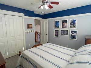 Bedroom featuring carpet, a textured ceiling, ceiling fan, and a closet