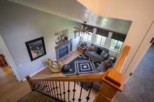 Living room with a ceiling fan, wood finished floors, a fireplace, and high vaulted ceiling