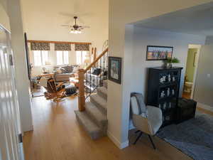Living area with light wood-style floors, stairs, and ceiling fan