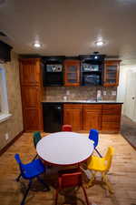 Bar area with a textured ceiling, light wood-type flooring, tasteful backsplash, black appliances, and recessed lighting