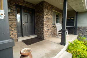 Property entrance with covered porch and stone siding
