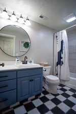 Full bath with tile patterned floors, vanity, shower / bath combo, and a textured ceiling