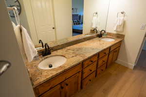 Ensuite bathroom featuring double vanity and light wood-style floors