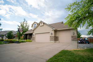 View of front of home featuring a garage, concrete driveway, and stone siding