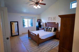Bedroom with vaulted ceiling, light wood-style flooring, and a ceiling fan