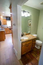 Bathroom with a textured ceiling, vanity, backsplash, and dark wood-type flooring