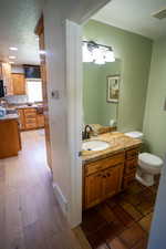 Half bathroom with a textured ceiling, vanity, and wood finished floors