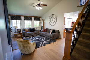 Living area with lofted ceiling, wood finished floors, stairway, ceiling fan, and a chandelier