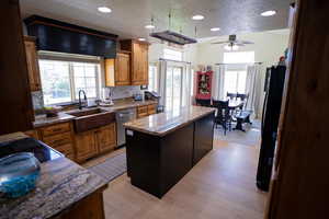 Kitchen with a center island, a textured ceiling, freestanding refrigerator, decorative backsplash, and brown cabinetry