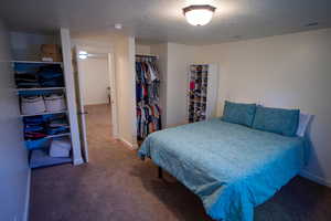 Carpeted bedroom featuring a textured ceiling and a closet