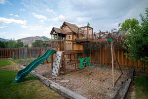View of playground with a fenced backyard and a mountain view