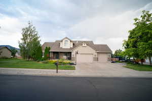 View of front facade with a garage, concrete driveway, a front lawn, a shingled roof, and stone siding
