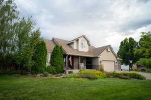View of front of house featuring a garage, a shingled roof, a porch, a front lawn, and driveway