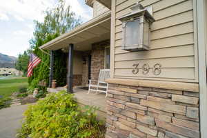 Property entrance with covered porch and stone siding