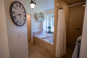 Bathroom featuring a bath, lofted ceiling, curtained shower, and tile patterned flooring