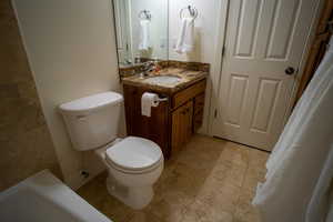 Full bath featuring vanity, tile patterned floors, and a tub to relax in