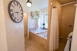 Full bath with a shower with curtain, a tub with jets, and vaulted ceiling