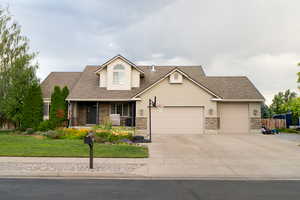 View of front of property with a porch, roof with shingles, an attached garage, and driveway