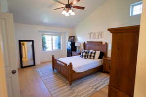 Bedroom featuring light wood-style flooring, a ceiling fan, and high vaulted ceiling