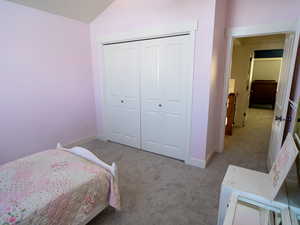 Bedroom with carpet flooring, a closet, and lofted ceiling