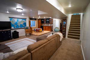 Living area featuring light colored carpet, stairs, a textured ceiling, and bar area