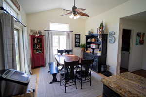 Dining area featuring light wood-style floors, ceiling fan, and high vaulted ceiling
