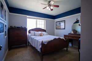 Carpeted bedroom with a textured ceiling and a ceiling fan