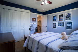 Bedroom with carpet, a closet, a ceiling fan, and a textured ceiling