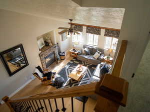Living room with a fireplace, light wood-type flooring, a textured ceiling, and ceiling fan