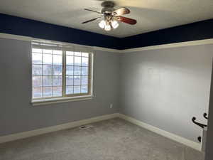 Empty room with light colored carpet, a ceiling fan, and a textured ceiling