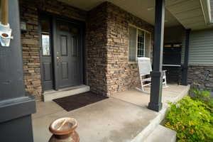 Doorway to property featuring a porch and stone siding