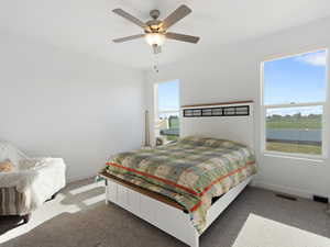 Bedroom with carpet flooring, a water view, and ceiling fan