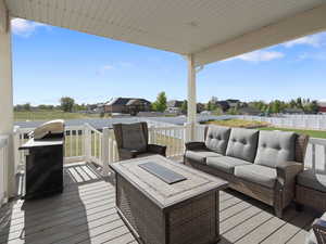 Wooden deck with an outdoor living space, a grill, and a residential view