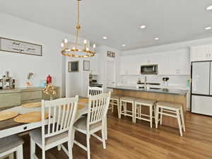 Dining space with a chandelier, light wood finished floors, and recessed lighting
