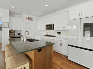 Kitchen featuring appliances with stainless steel finishes, tasteful backsplash, dark wood finished floors, white cabinets, and recessed lighting
