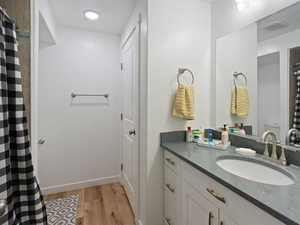 Bathroom featuring wood finished floors, vanity, and curtained shower
