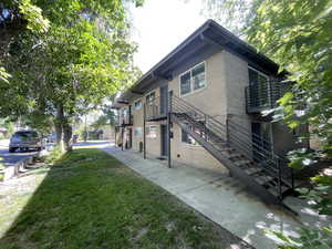 View of side of property featuring stairway, brick siding, and a lawn