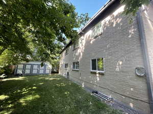 View of home's exterior with a storage unit, a yard, and brick siding