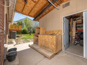 View of covered patio with a mountain view, leading to a large insulated shed (featuring AC and Heater)