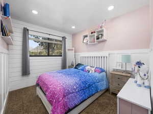 Bedroom with dark colored carpet, recessed lighting, wooden walls, and a wainscoted wall