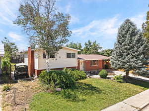Tri-level home featuring a front yard and brick siding