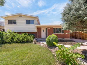 Multi-level home with brick siding, mature trees, a carport, and concrete driveway