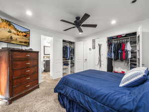 Master Bedroom featuring carpet flooring, ornamental molding, recessed lighting, ensuite bathroom, two closets, and ceiling fan