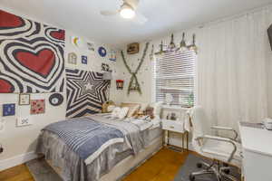 Bedroom featuring wood finished floors, ceiling fan, and a desk