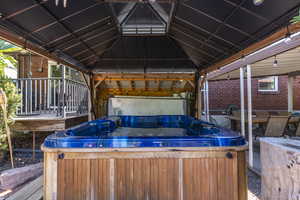 Wooden terrace featuring a hot tub and a gazebo