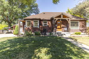 View of front of home with brick siding, a front lawn, and a shingled roof