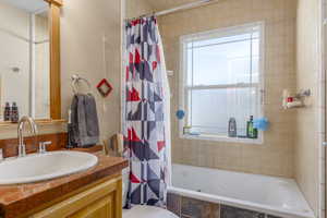 Bathroom with tiled shower / bath combo and vanity